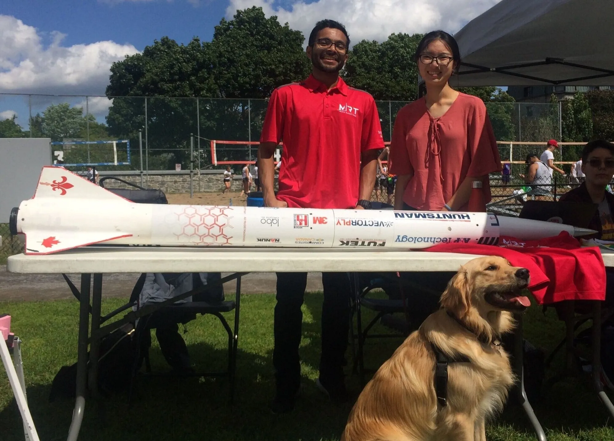 Two team members tabling at an event with a used rocket.