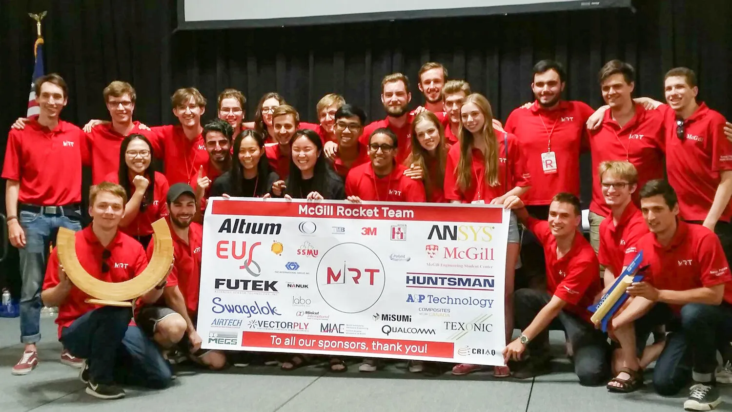The McGill Rocket Team poses with their rocket and team banners.
